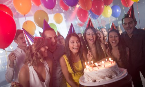 Woman with friends celebrating on her birthday party and about to blow the candles on the cake