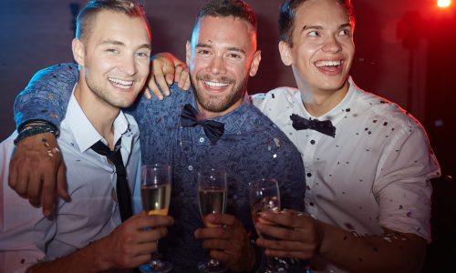 Three elegant guys holding flutes with champagne