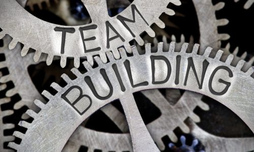 Macro photo of tooth wheel mechanism with TEAM BUILDING letters imprinted on metal surface